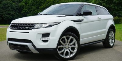 Stylish white Range Rover parked on a road in a green outdoor setting, showcasing its luxury design.
