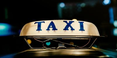 Close-up view of an illuminated taxi sign in a bustling city at night.